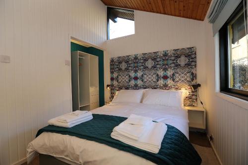 a bedroom with a bed with towels on it at Cosy Modern Nordic Lodge w/ Loch View & Log Burner in Lochearnhead