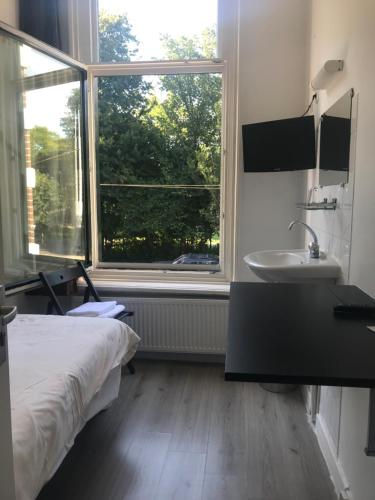 een slaapkamer met een bed, een wastafel en een raam bij hotel Oosterpark in Amsterdam
