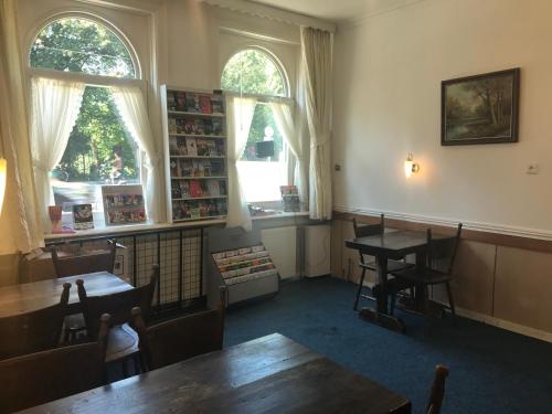 een kamer met een tafel en stoelen en 2 ramen bij hotel Oosterpark in Amsterdam