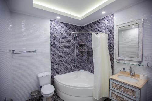 a bathroom with a toilet and a shower and a sink at Hotel Ak Saray in Tashkent
