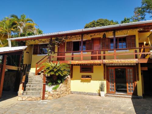 a yellow building with a staircase in front of it at 3 Palmeiras Guest Lounge in Miguel Pereira