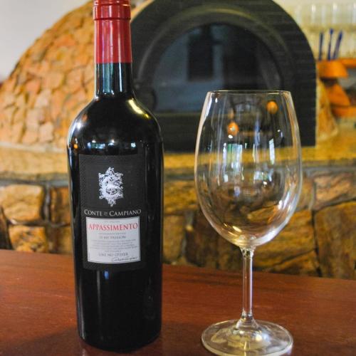 a bottle of wine sitting next to a wine glass at 3 Palmeiras Guest Lounge in Miguel Pereira