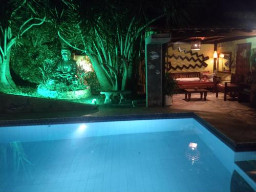 a swimming pool with a fountain in a yard at night at 3 Palmeiras Guest Lounge in Miguel Pereira