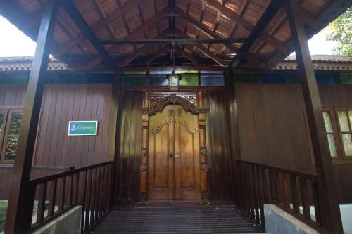 a wooden door of a house with a sign on it at De Serenity - Exclusive Jungle Retreat in Seremban