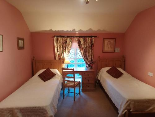two beds in a room with a desk and a window at Kilmokea Garden Suite in New Ross