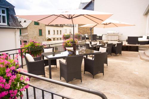 a patio with tables and chairs and umbrellas at Gästehaus C.H.Berres Ürzig-Mosel in Ürzig