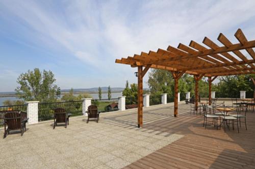 a patio with tables and chairs and a wooden pergola at Atrium Agárd Panzió in Gárdony