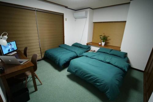 a bedroom with two pillows and a desk with a computer at ゲストハウス八街 in Yachimata