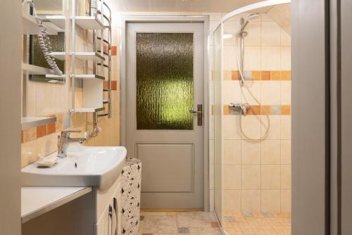 a bathroom with a sink and a shower and a door at Namelis prie Širvintos upės su pirtimi in Širvintos