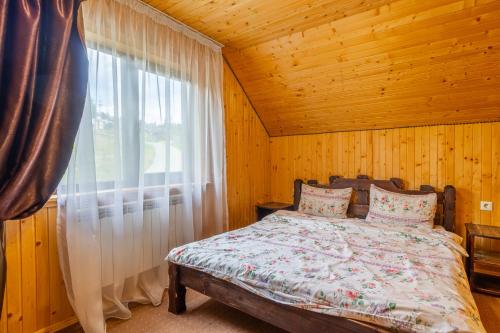 a bed in a wooden room with a window at Holiday home shale in Bukovel