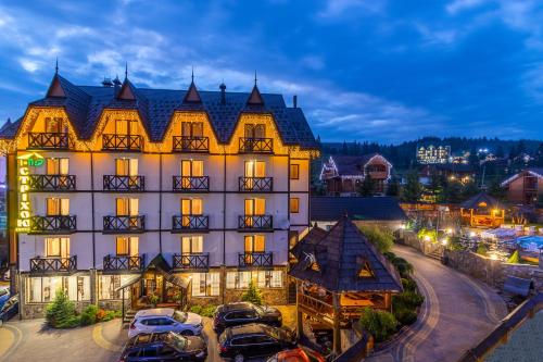 a large building with cars parked in front of it at Hotel Pid Strihoju in Bukovel