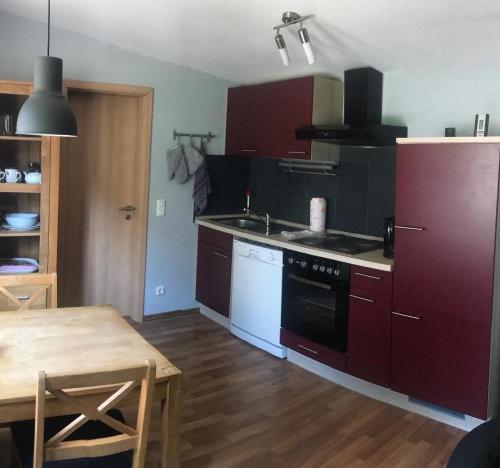 uma cozinha com armários vermelhos e uma mesa de madeira e uma mesa e uma mesa de mesa em Ferienhaus im Ostertal em Sankt Wendel