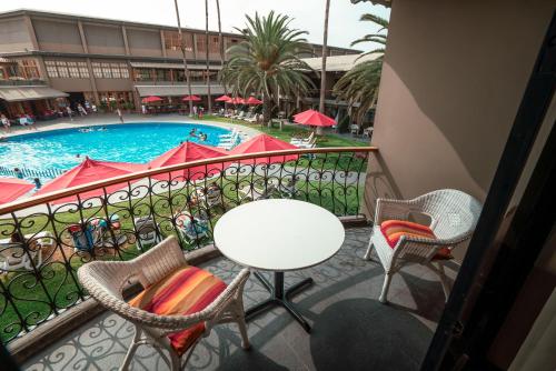 a balcony with a table and chairs and a pool at Costa del Sol Wyndham Trujillo in Trujillo