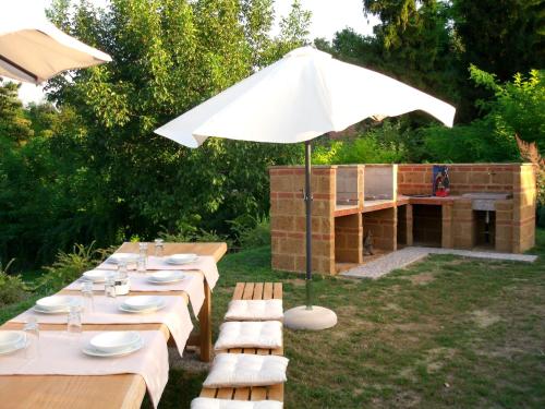 a group of tables with an umbrella in a yard at Casa sull'Albero Aromantica in San Salvatore Monferrato