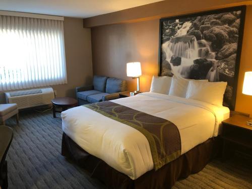 a hotel room with a large bed and a couch at Super 8 by Wyndham Lynnwood in Lynnwood