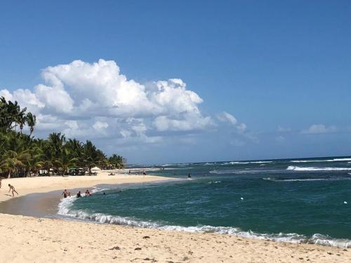 a beach with a group of people swimming in the ocean at La Gaviota B3 in Juan Dolio