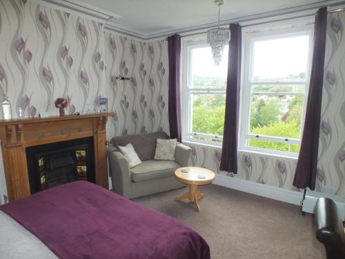 a bedroom with a bed and a chair and a fireplace at Glan Heulog in Conwy