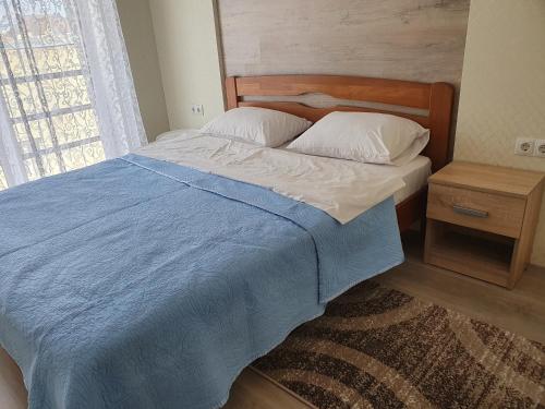 1 dormitorio con 1 cama con manta azul y ventana en квартира в центрі міста, новобудова, en Lutsk