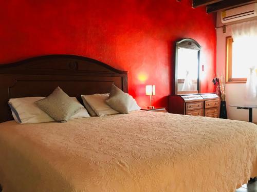 1 dormitorio con 1 cama grande y pared roja en Posada Temazcal Santo Domingo, en Tepoztlán