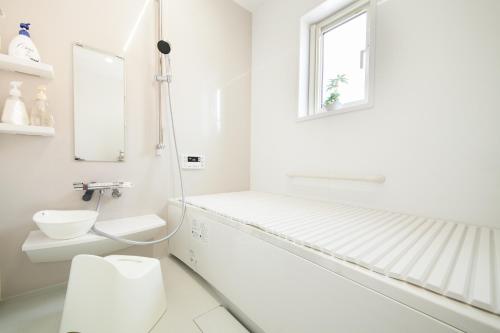 La salle de bains blanche est pourvue de toilettes et d'une fenêtre. dans l'établissement 那須塩原にある貸別荘 レンガの家Ｓｏｒａ, à Nasushiobara