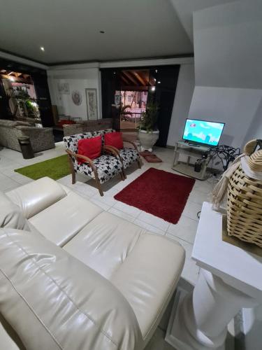 a living room with a white couch and a television at VITORIA GARDEN in Águas de Lindóia
