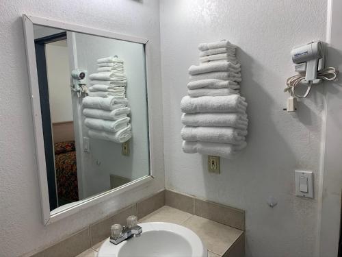 Un baño con lavabo, espejo y toallas. en Budget Lodge Inn - Abilene, en Abilene