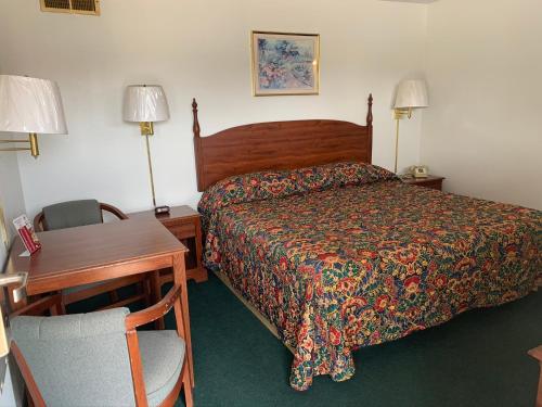 Un dormitorio con una cama, un escritorio y una silla. en Budget Lodge Inn - Abilene, en Abilene