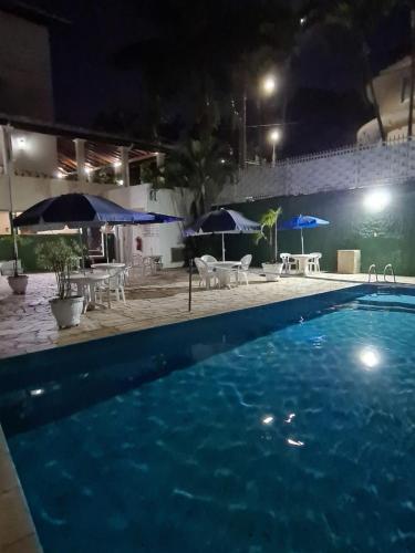 a swimming pool at night with tables and umbrellas at VITORIA GARDEN in Águas de Lindóia