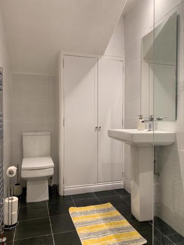 a white bathroom with a toilet and a sink at 5a Bank Street in Keswick