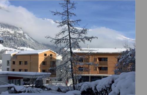 a building in the snow with a tree in the foreground at Montanas - Luxuswohnung mit Kamin - Nahe Caumasee & Talstation in Flims