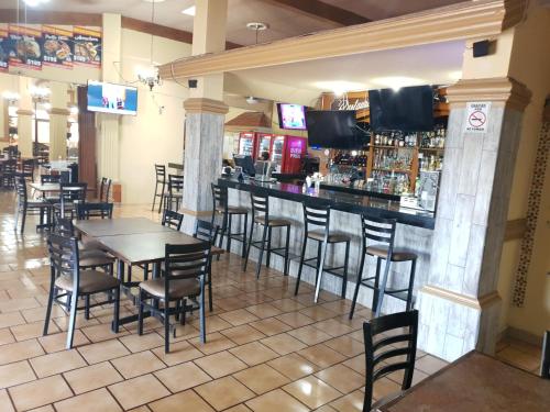 a restaurant with a bar with tables and chairs at Hotel Posada Santa Fe Sabinas in Sabinas