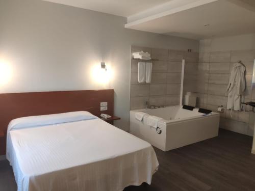 a white bath room with a white tub and a white bed at Motel Caldas in Caldas de Reis