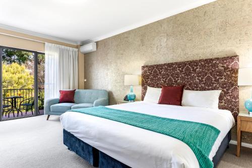 a bedroom with a large bed and a chair at Berry Village Boutique Motel in Berry