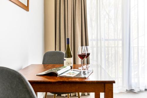 a wooden table with a bottle of wine and a glass at Berry Village Boutique Motel in Berry