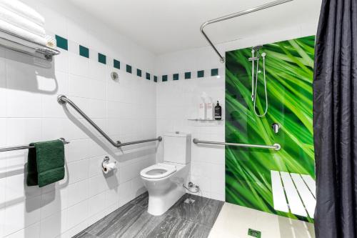 a bathroom with a toilet and a green painting on the wall at Berry Village Boutique Motel in Berry