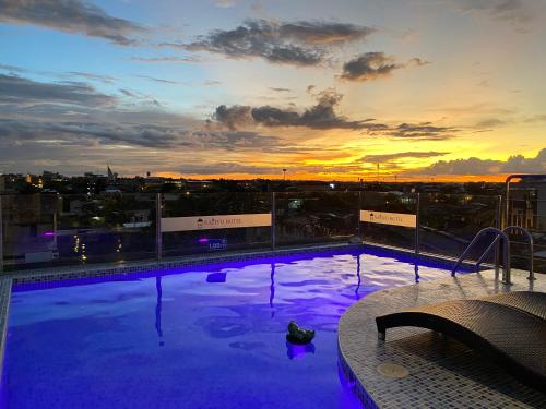 a swimming pool on top of a building with a sunset at Nativo Hotel in Iquitos