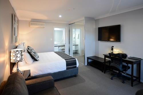 Un dormitorio con una cama y un escritorio con una computadora. en Astro Dish Motor Inn, en Parkes