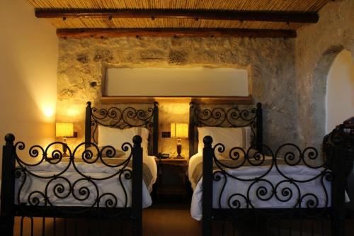 two beds in a bedroom with a stone wall at Kemerli Konak Boutique Hotel in Kyrenia