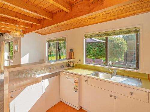 una cucina con lavandino e finestra di Sea Breeze Sanctuary - Pauanui Holiday Home a Pauanui