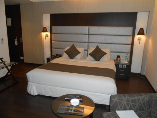 a hotel room with a large bed and a table at Southern Plaza in Kolkata