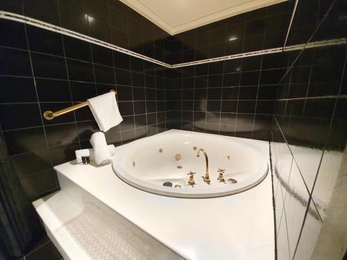 ein schwarz gefliestes Bad mit einer Badewanne in der Unterkunft Bell Motel in Melbourne