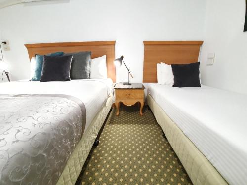 dwa łóżka siedzące obok siebie w pokoju hotelowym w obiekcie Bell Motel w Melbourne