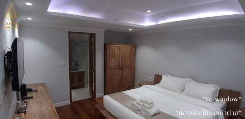 a bedroom with a white bed and a television at Lanna Oriental Hotel in Chiang Mai