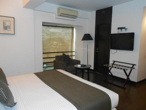 a hotel room with a bed and a television at Southern Plaza in Kolkata