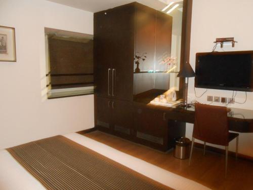 a room with a desk and a television and a cabinet at Southern Plaza in Kolkata