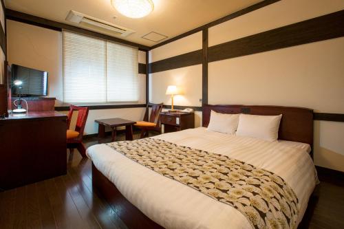 Habitación de hotel con cama, escritorio y habitación en Wasuki Tsukasakan, en Kumamoto