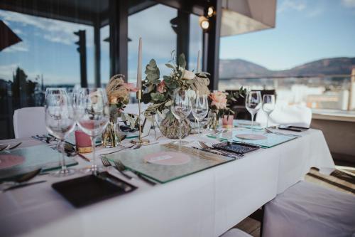 a white table with glasses and flowers on it at voco Villach by IHG in Villach