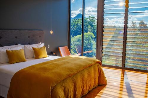 a bedroom with a large bed and a large window at Glass On Glasshouse in Glass House Mountains