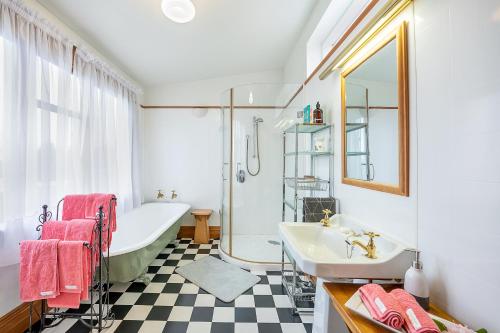 a bathroom with a bath tub and a sink and a bath tub at The Fern & Thistle Luxury Accommodation in Balclutha