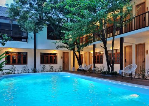 a swimming pool in front of a building with trees at Hotel AONO in Chiang Mai